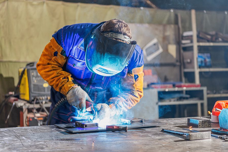 Man welding a metal plate for a custom fabrication job.