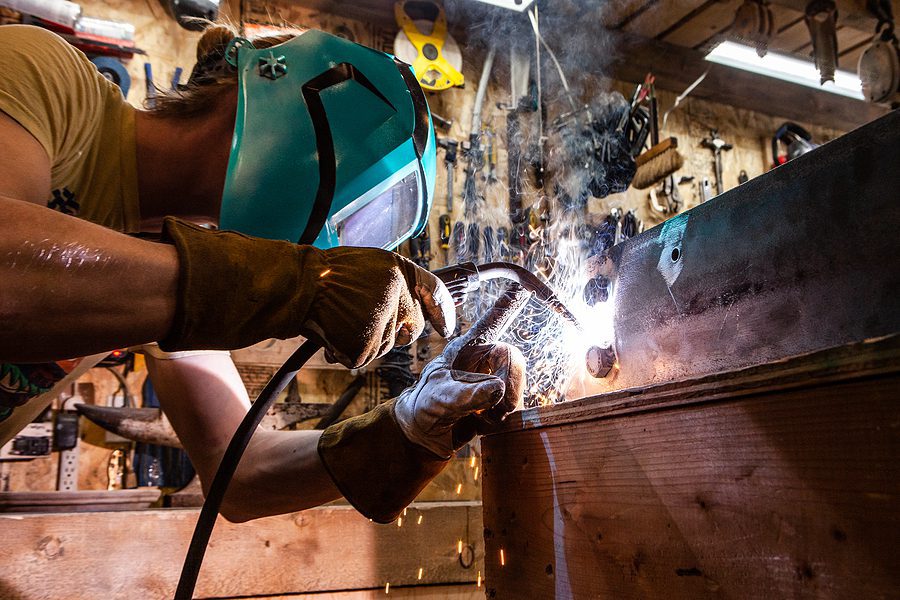 A closeup view of a skilled tradesman operating a metal inert gas welder to join the corners of two steel beams. Process of a metalworker at work.
