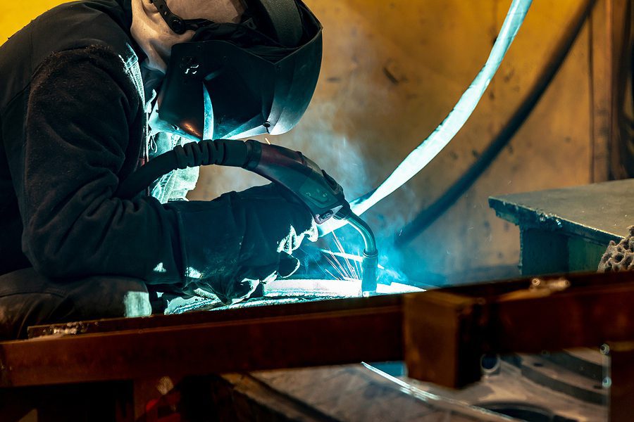 Professional welder working in a custom steel fabrication shop.
