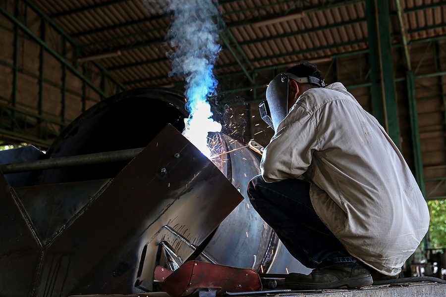 Man welding in a fabrication shop.