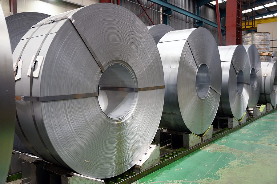 Large rolls of steel being stored in a warehouse.