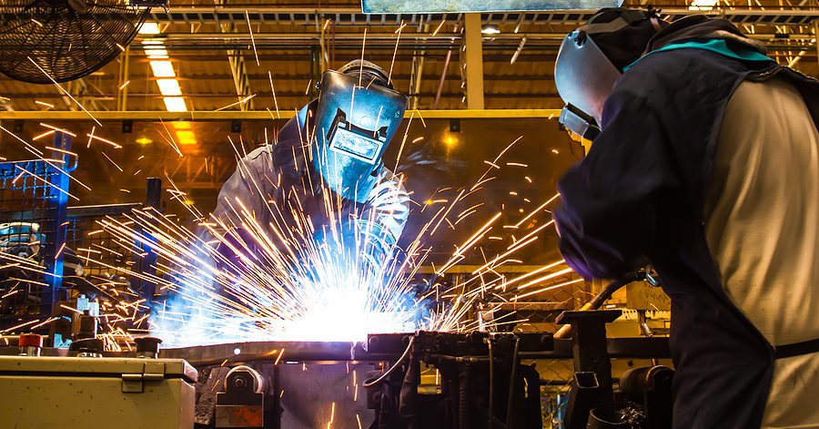Industrial welder working on a custom metal fabrication project wearing protective gear.