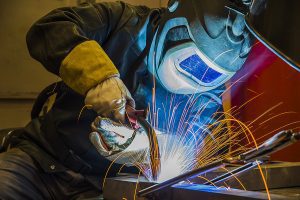 Close up of a welder working on a project with sparks flying. 