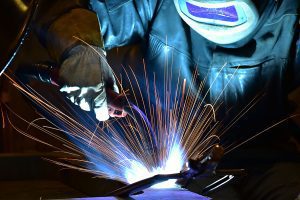 Welder wearing protective gear, working on a project with sparks flying. 