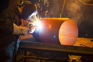 Welder working on a project wearing protective gear with sparks flying. 