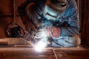 Welder working in a factory wearing protective gear. 