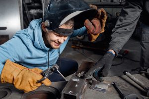 Male welder receiving on-the-job training. 