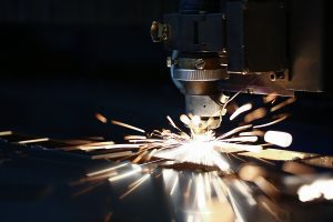 Sparks flying out of a CNC machine that is cutting metal. 