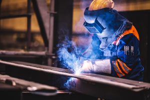 Welder working in an industrial manufacturing factory with sparks flying. 