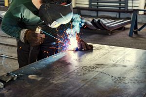 Industrial welder working on a large project with sparks flying.