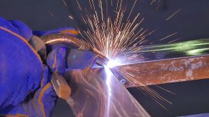 Close up view of a welder working on steel frame with sparks. 