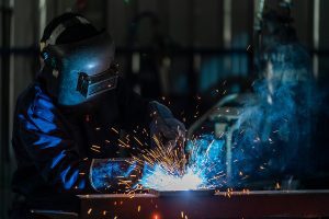 Welder wearing protective gear and welding with sparks flying. 