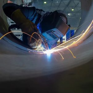 Welder working on a project wearing protective gear with sparks. 